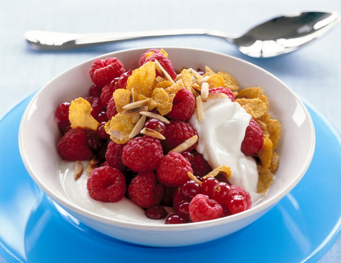 Salad with raspberries, almonds, cereals and yogurt in bowl