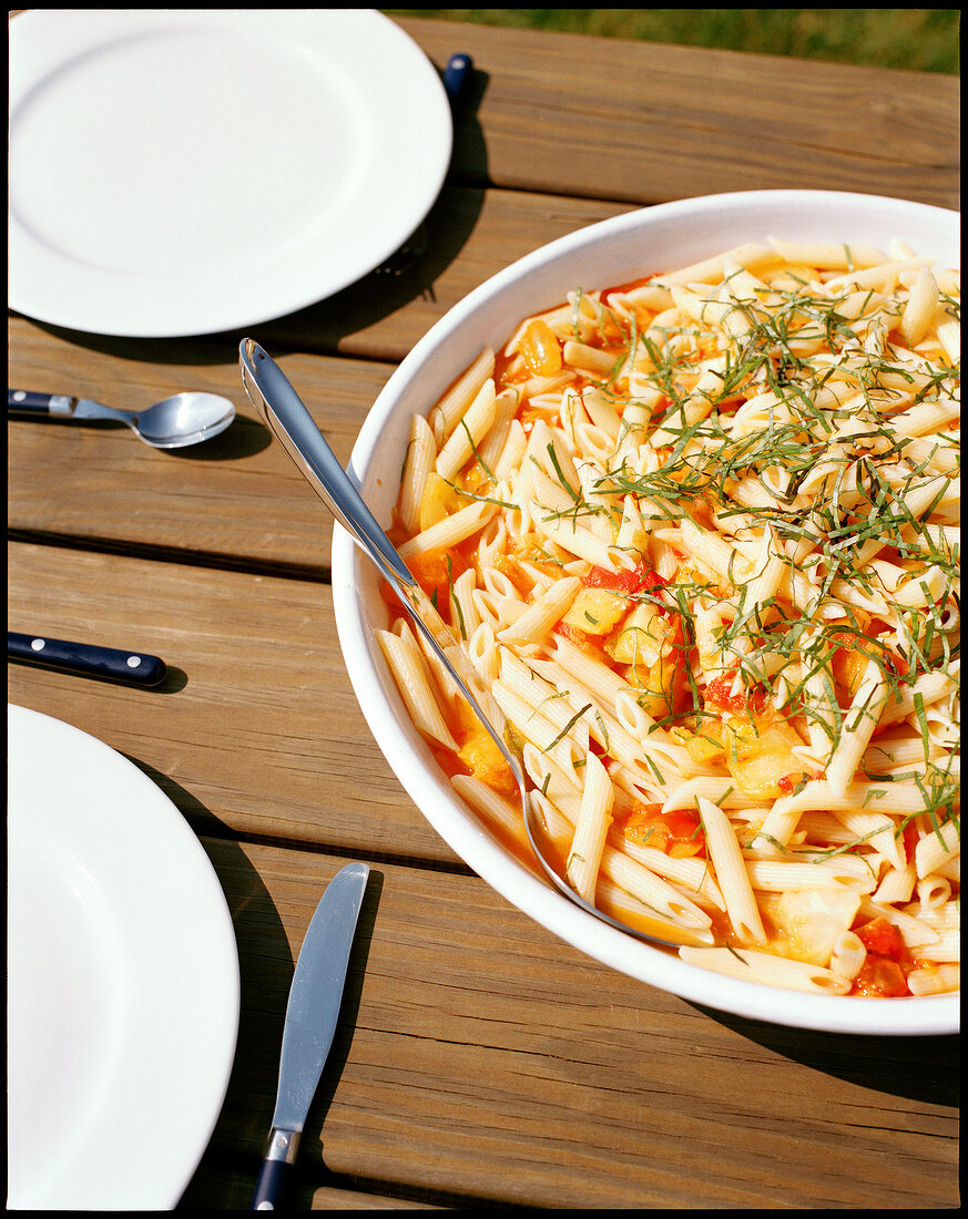 Large bowl of penne pasta on a wooden table