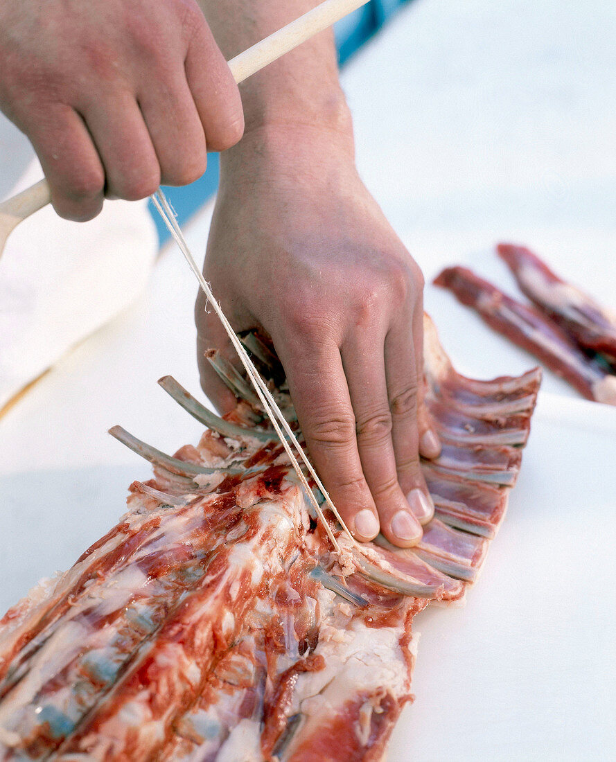 Close-up of man's hands chopping rack of lamb