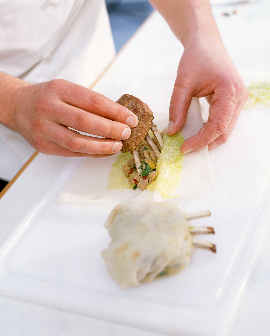 Close-up of a man's hands filling filo pastry with rack of lamb