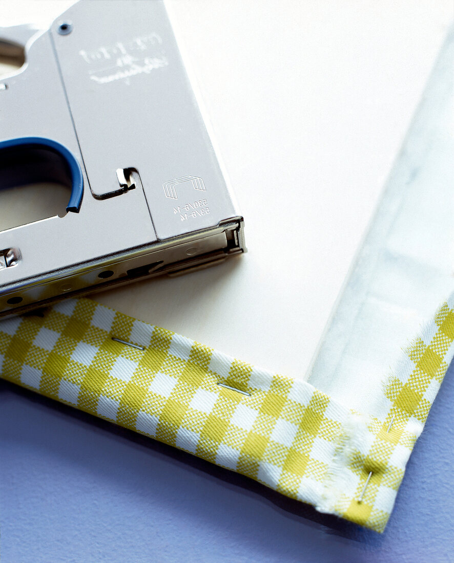 Close-up of pinboard with stapled green plaid fabric in vichy style