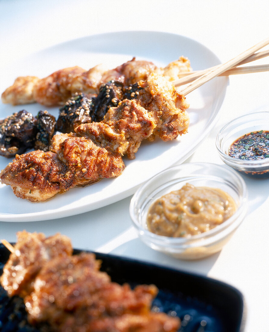 Satay skewers on plate with two sauces