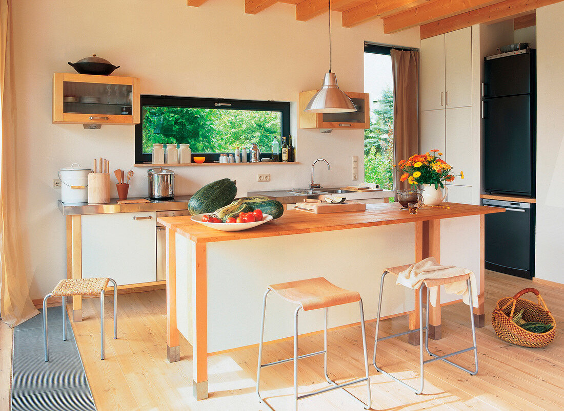 Bright kitchen with table and wooden stools in front of kitchen counter