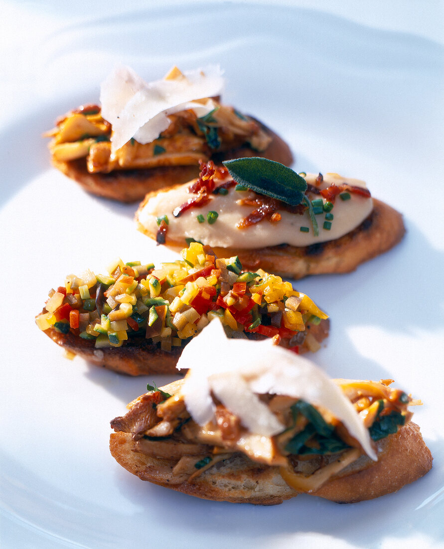 Close-up of crostini topped with chanterelle mushrooms, mashed beans and ratatouille