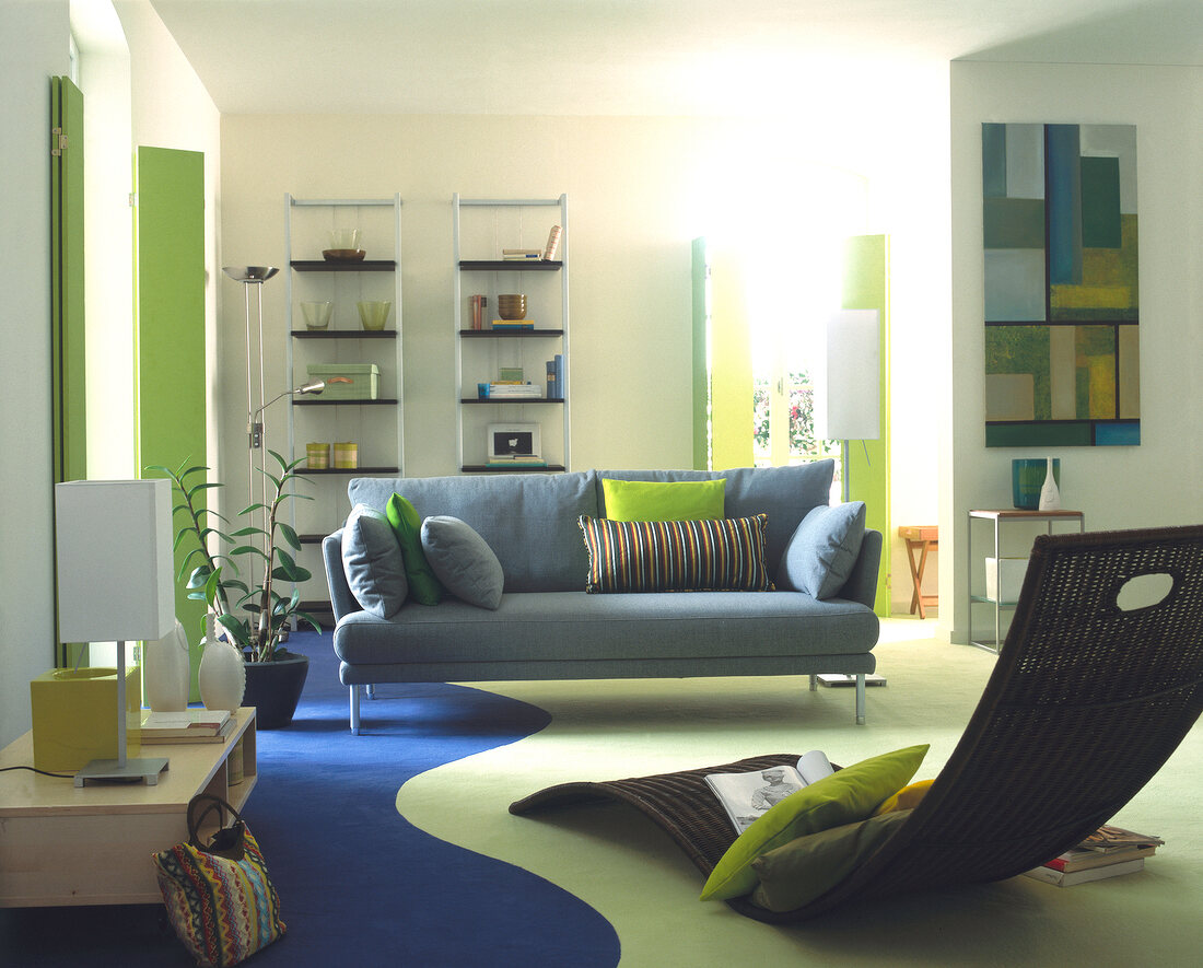 View of living room with gray sofa wooden shelves and lounge chair