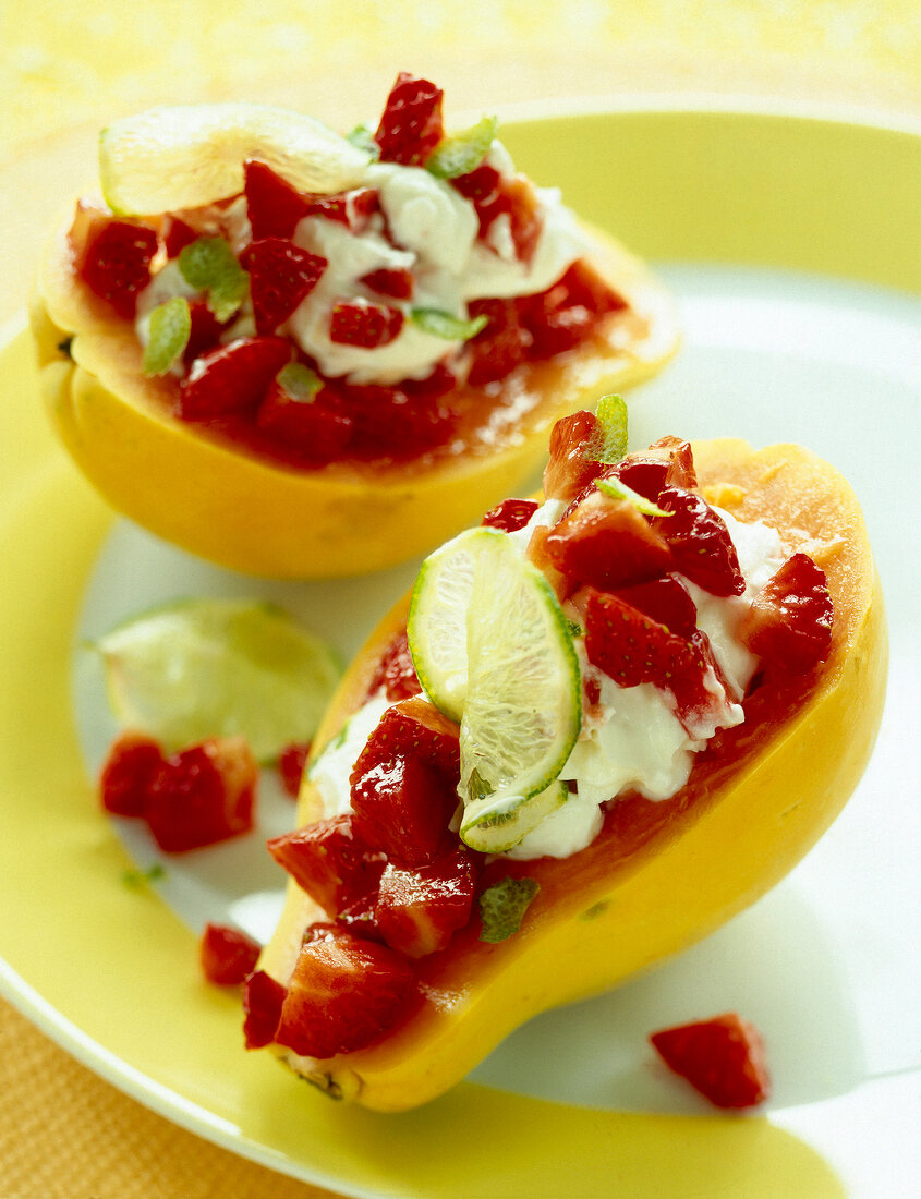 Close-up of papaya with chopped strawberries, lime and curd on plate