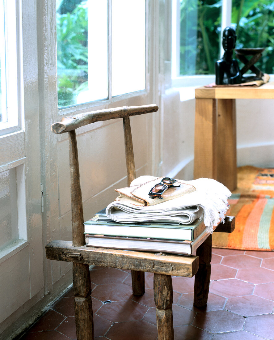 Afrikanischer Holzstuhl dient als Ablage für Schal und Bücher