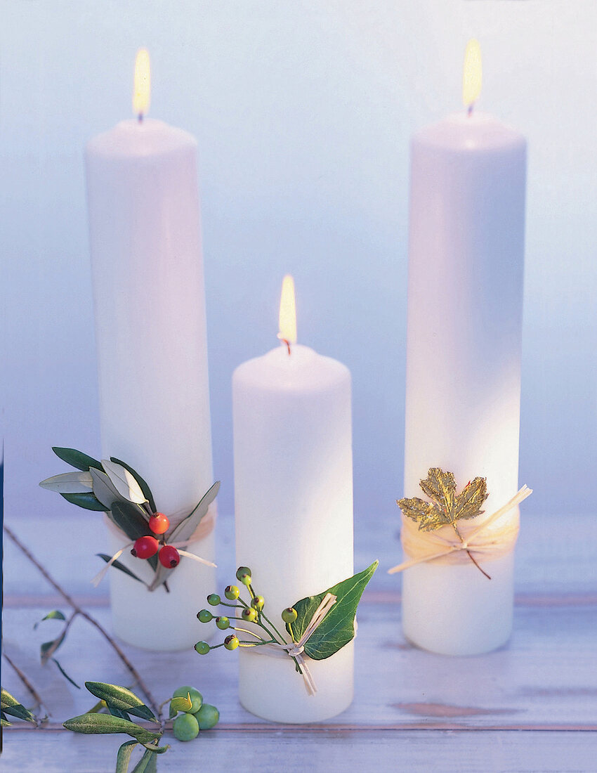 3 dicke, weiße Kerzen, verziert mit Beeren und vergoldeten Blättern