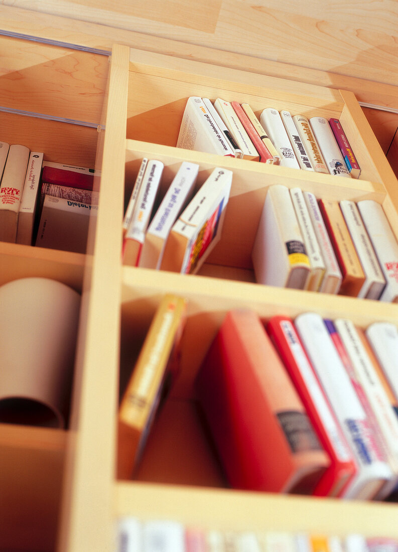 Books arranged in wooden self, low angle view