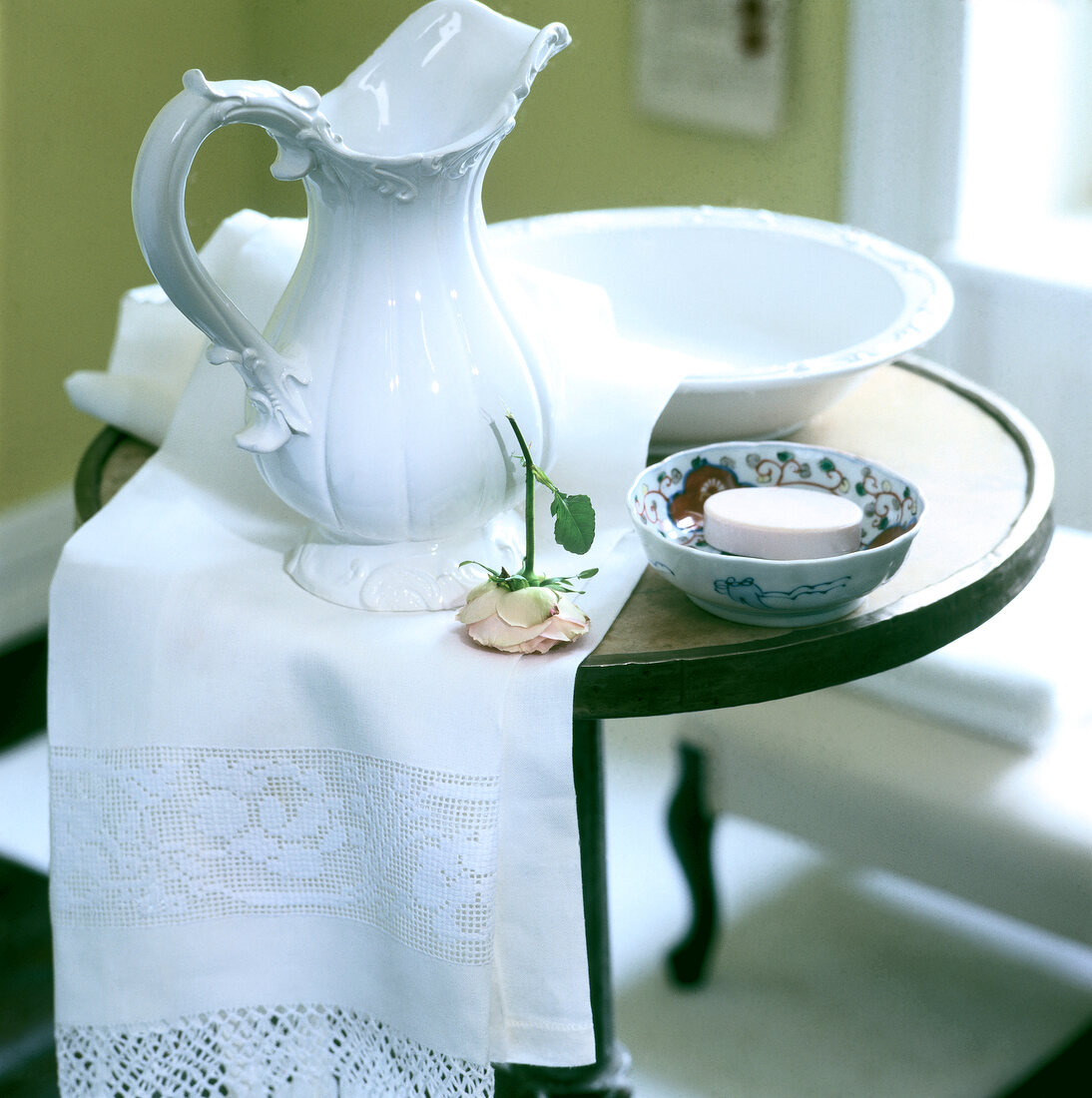 White water jug, bowl, towel, soap and rose on table 