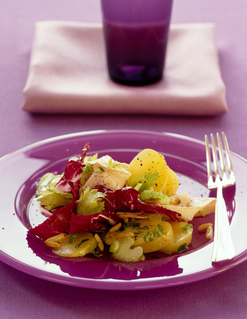 Potato salad with celery, radicchio and pine nuts on plate