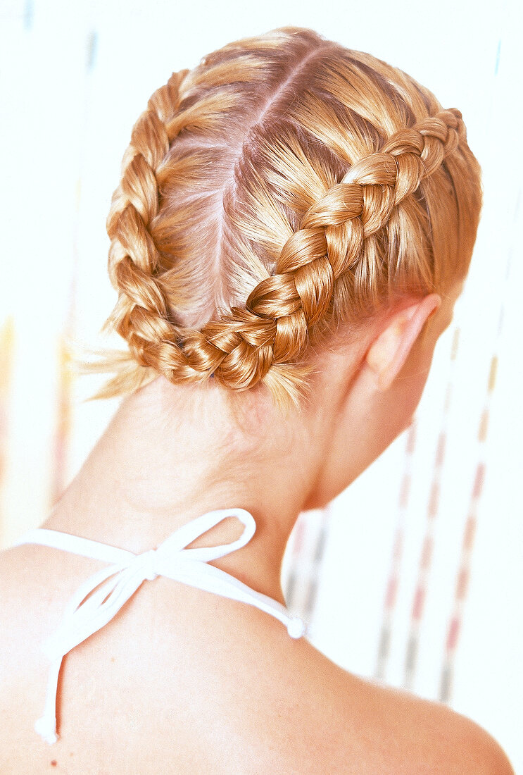 Rear view of woman with golden blonde hair pinned up in two braids