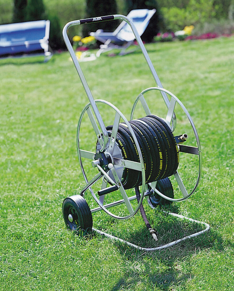 Schlauchwagen für Rasensprenger steht auf der Rasenfläche