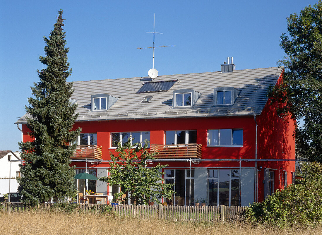 Haus mit Feuerrotem Putz und Holz- und Metalelementen