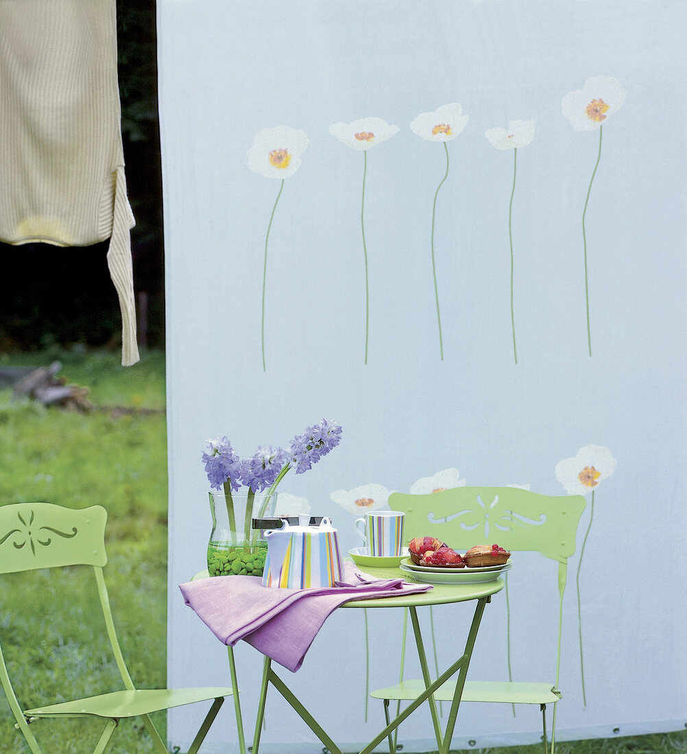Streifenservice mit Tee + Törtchen auf hellgrünem Bistrotisch im Garten