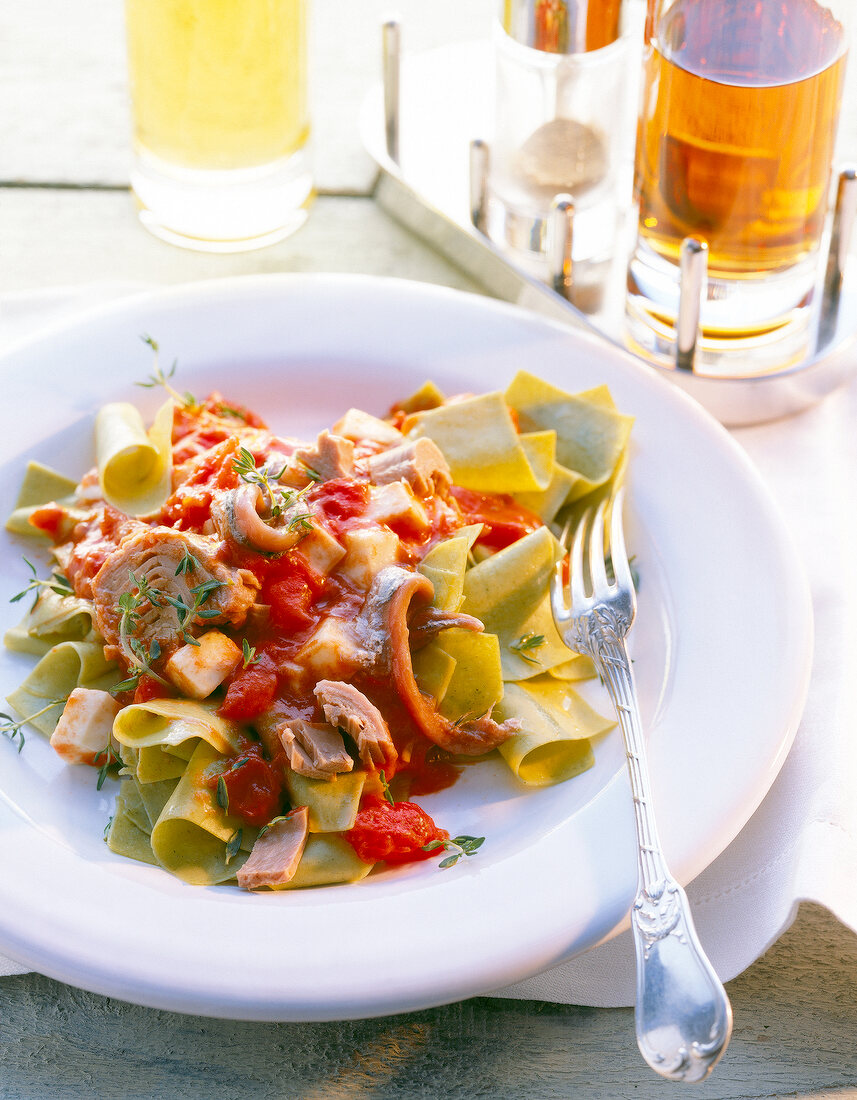 Close-up of green ribbon pasta with tuna sauce on plate with a fork