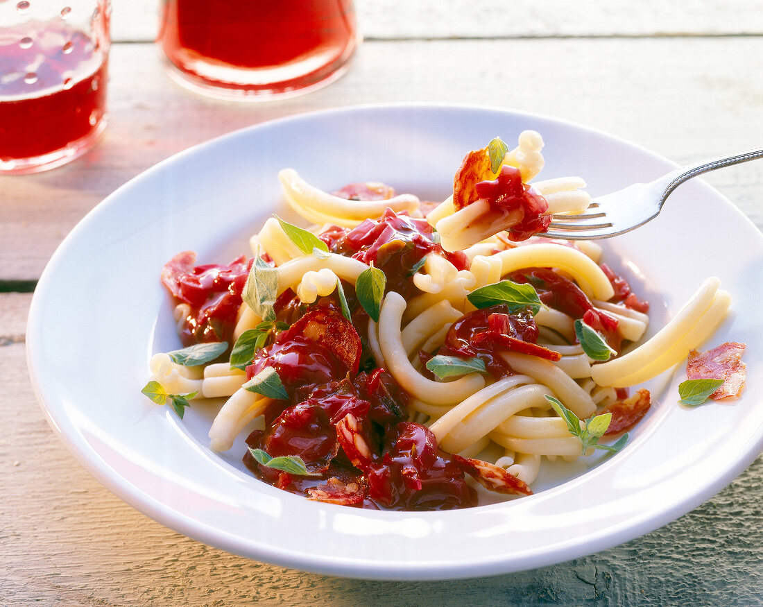 Rigatoni in red onion sauce on plate with a fork