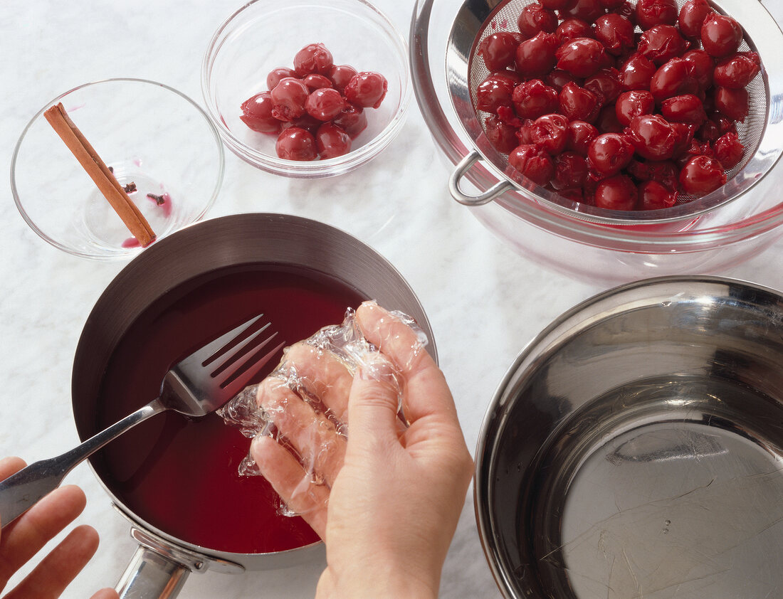 Close-up of cherry pulp sauce in saucepan with a fork