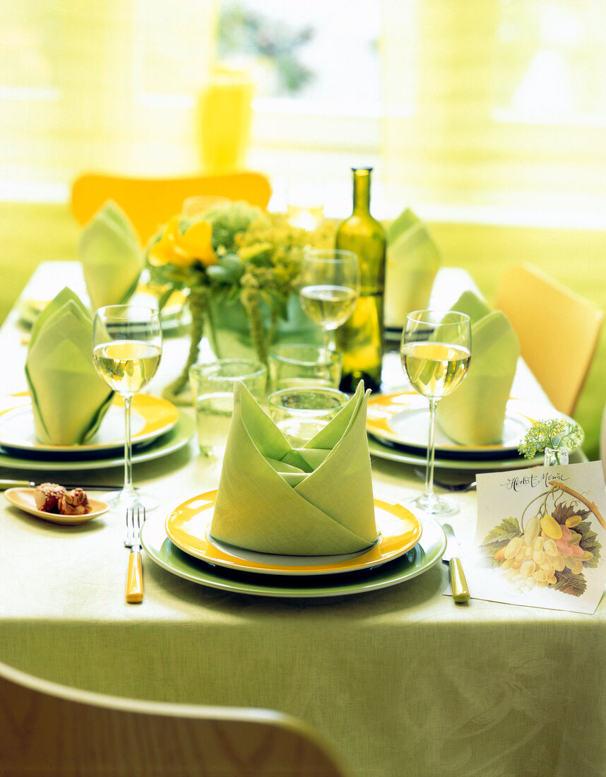 Decorated table with green table cloth and folded napkins on plates