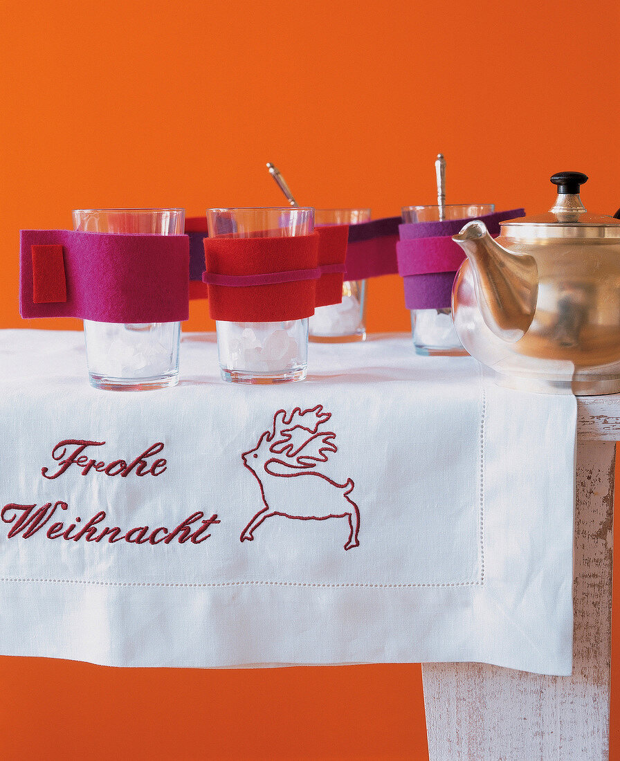 Glasses in colourful felt cuffs placed on embroidered table linen