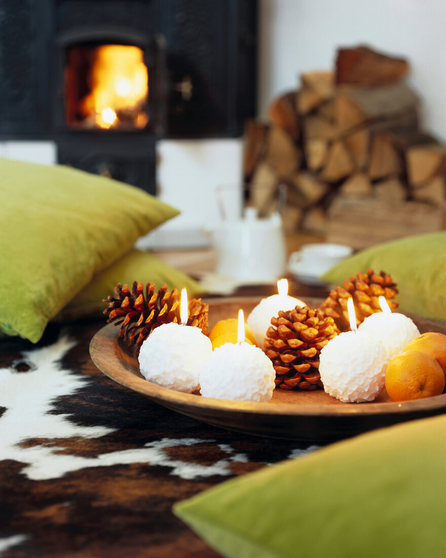 Snow ball candles, pine cones and citrus fruits in wooden bowl