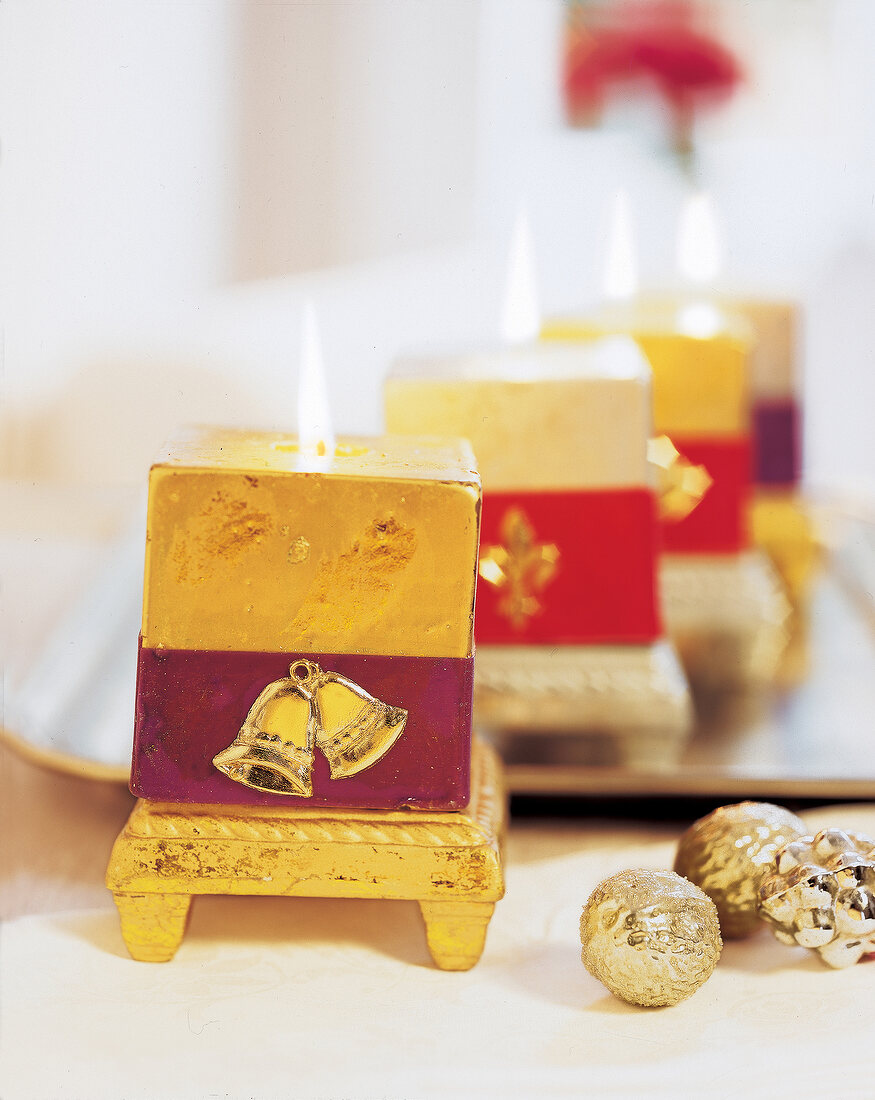 Close-up of golden square lit candles on table