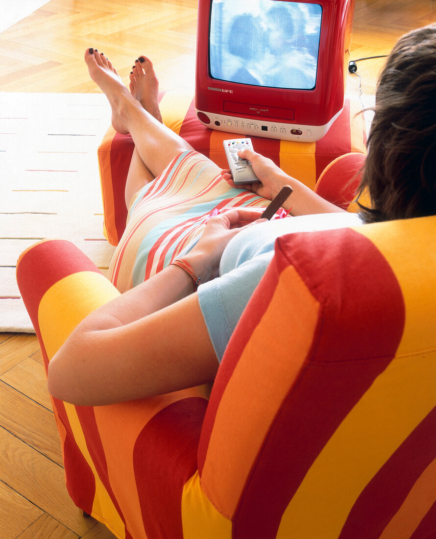 Rear view of woman sitting on chair and watching television