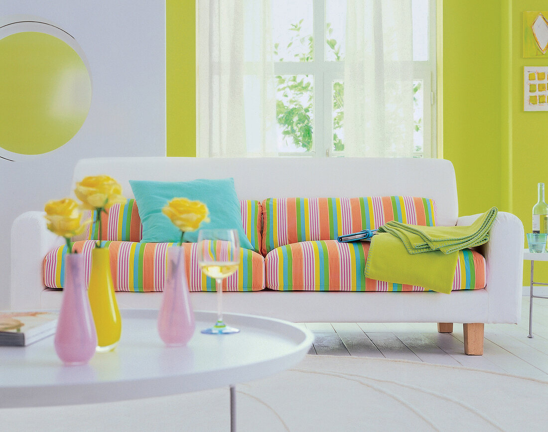 Weißes Sofa mit gestreiften Polstern und Couchtisch. Wände in hellem Grün