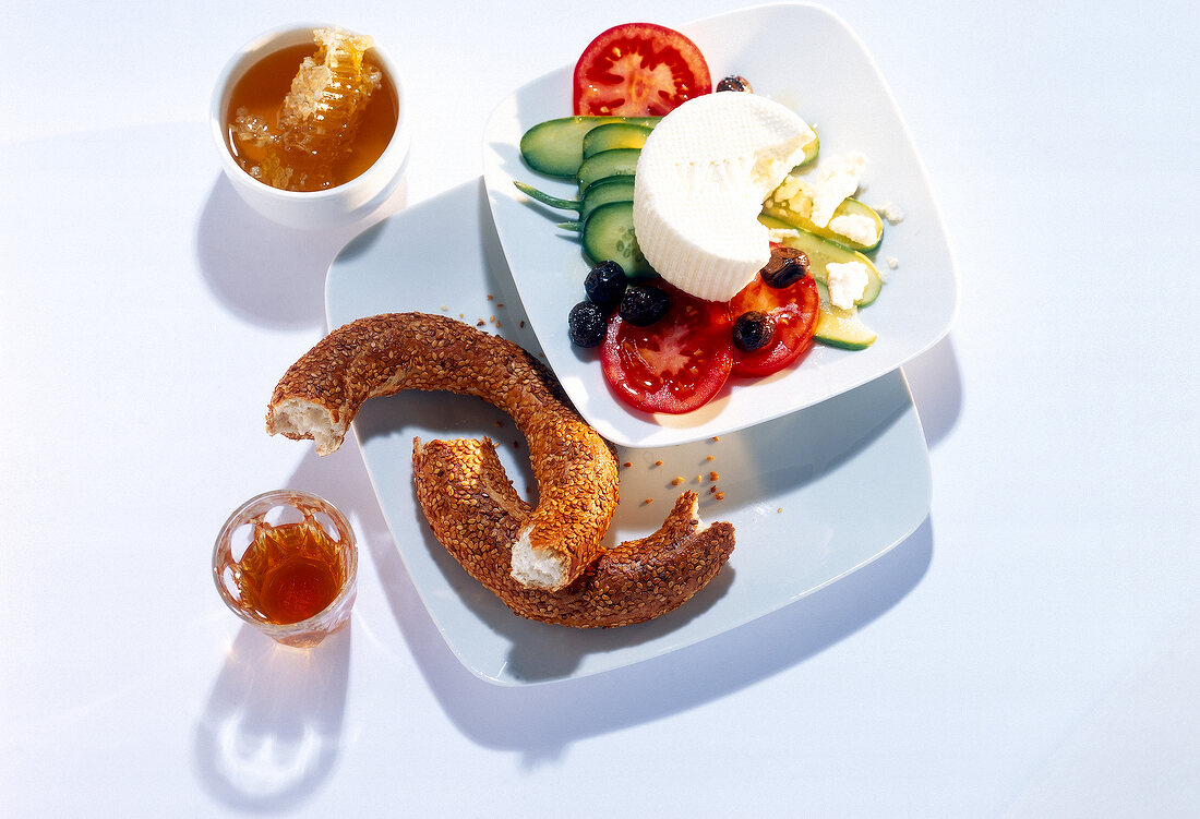 Breakfast table set with salad, sheep cheese, tea, honey and sesame bread on plate