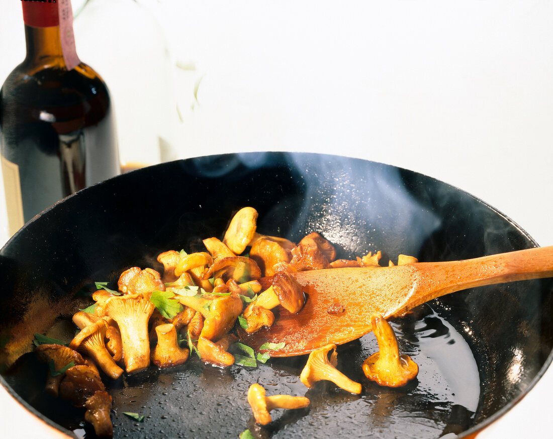 Close-up of mushrooms with wooden spoon in frying pan