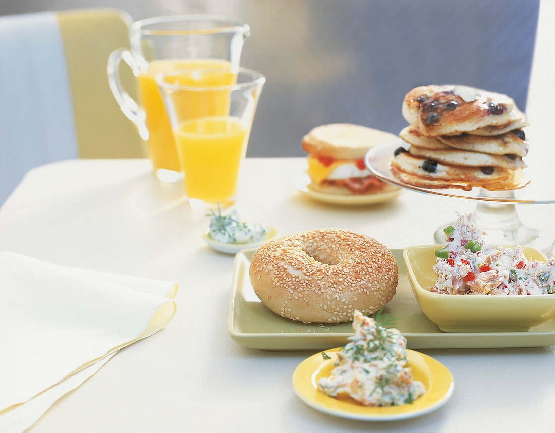 Bagel with bowl of tuna spread served on plate