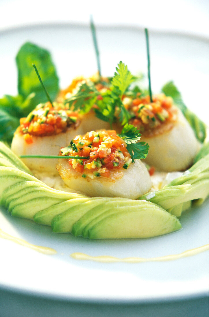 Close-up of scallops with avocado slices on plate