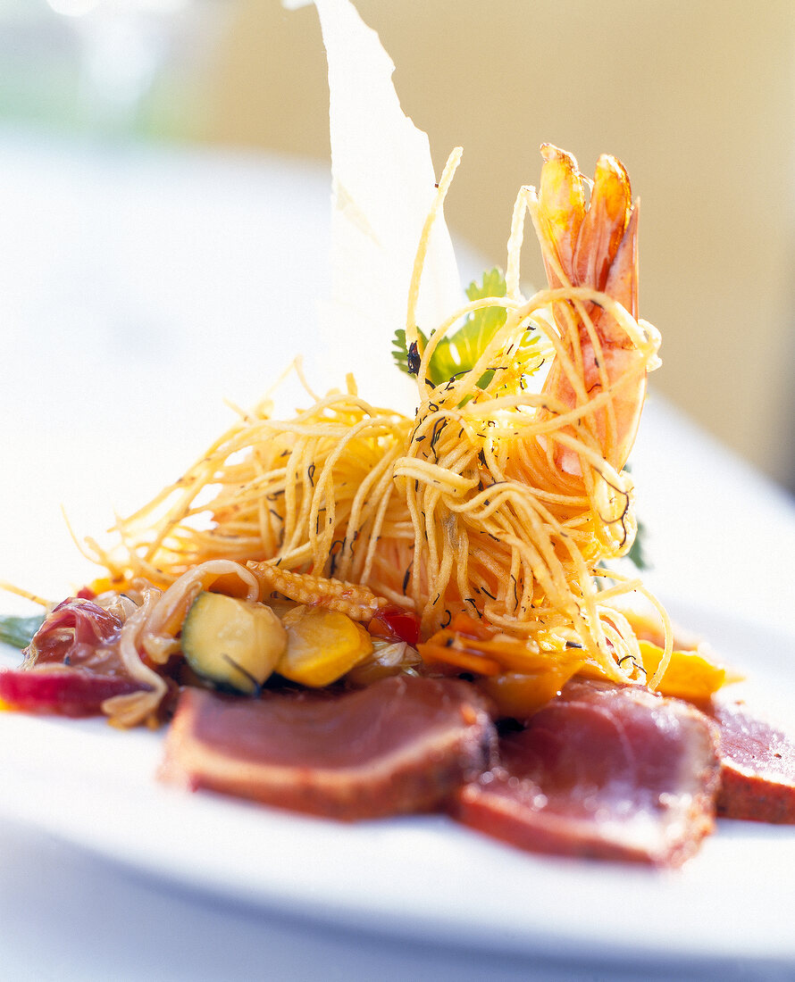 Close-up of marinated tuna fish with vegetables, shrimp and fried noodles