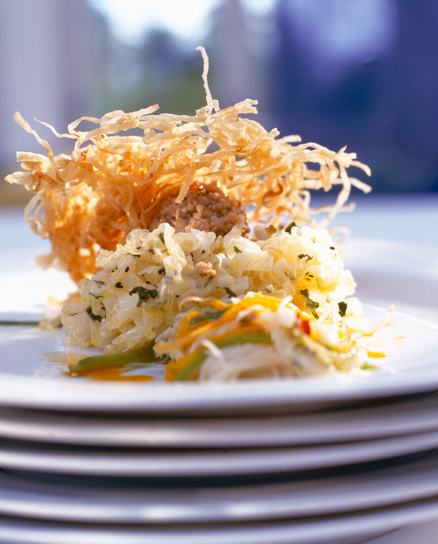 Close-up of baked veal tartare with fried noodles and glass noodle salad on plate