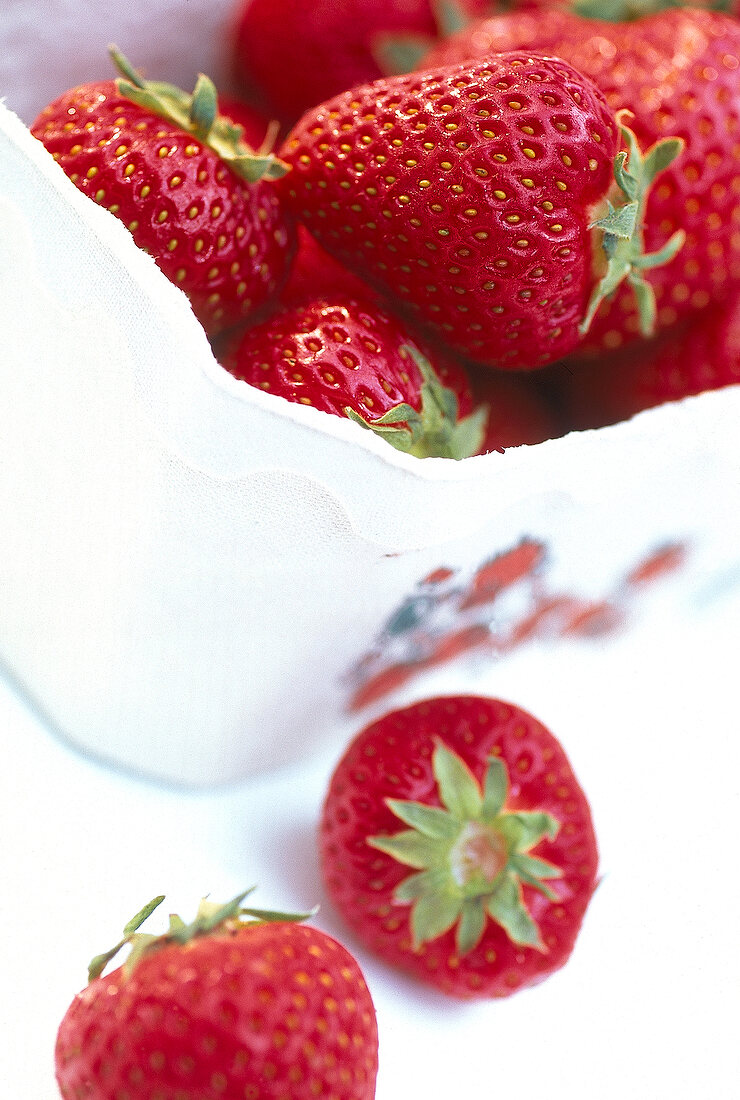 Close-up of strawberries in bowl and on white surface