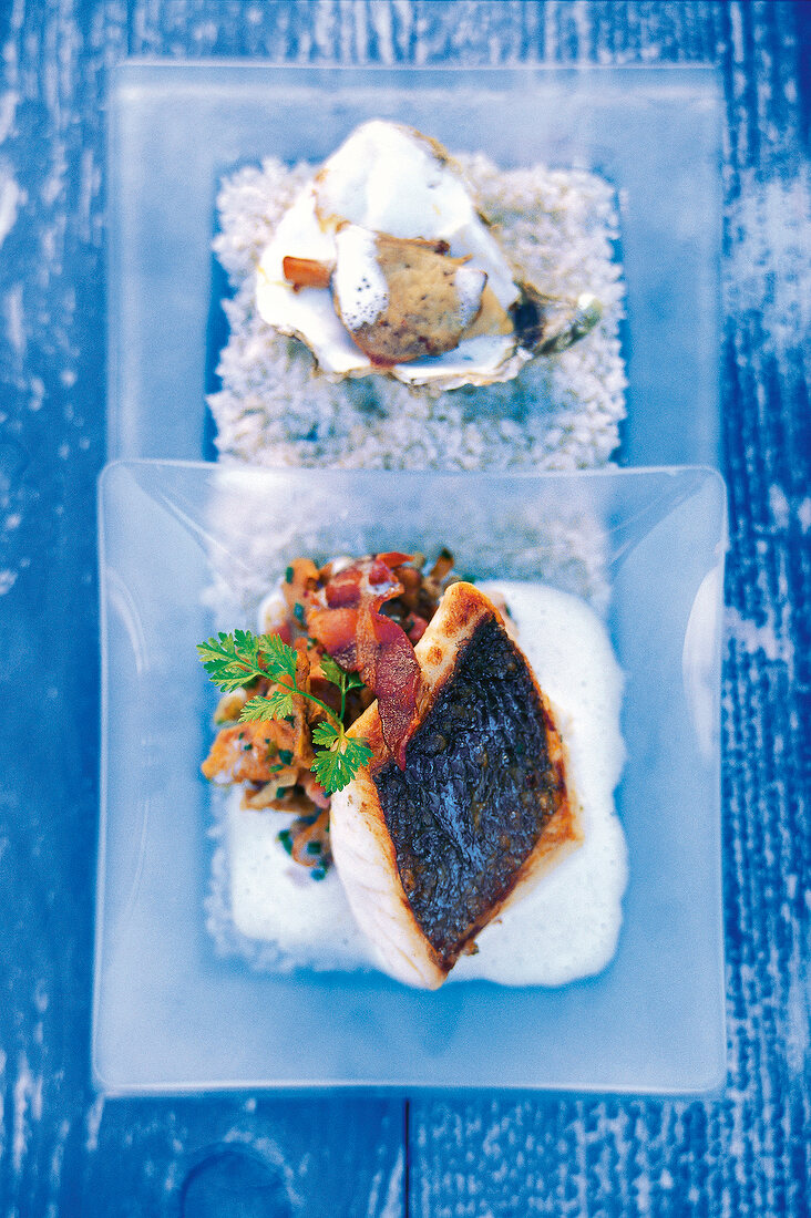 Catfish garnished with bacon on square glass plate