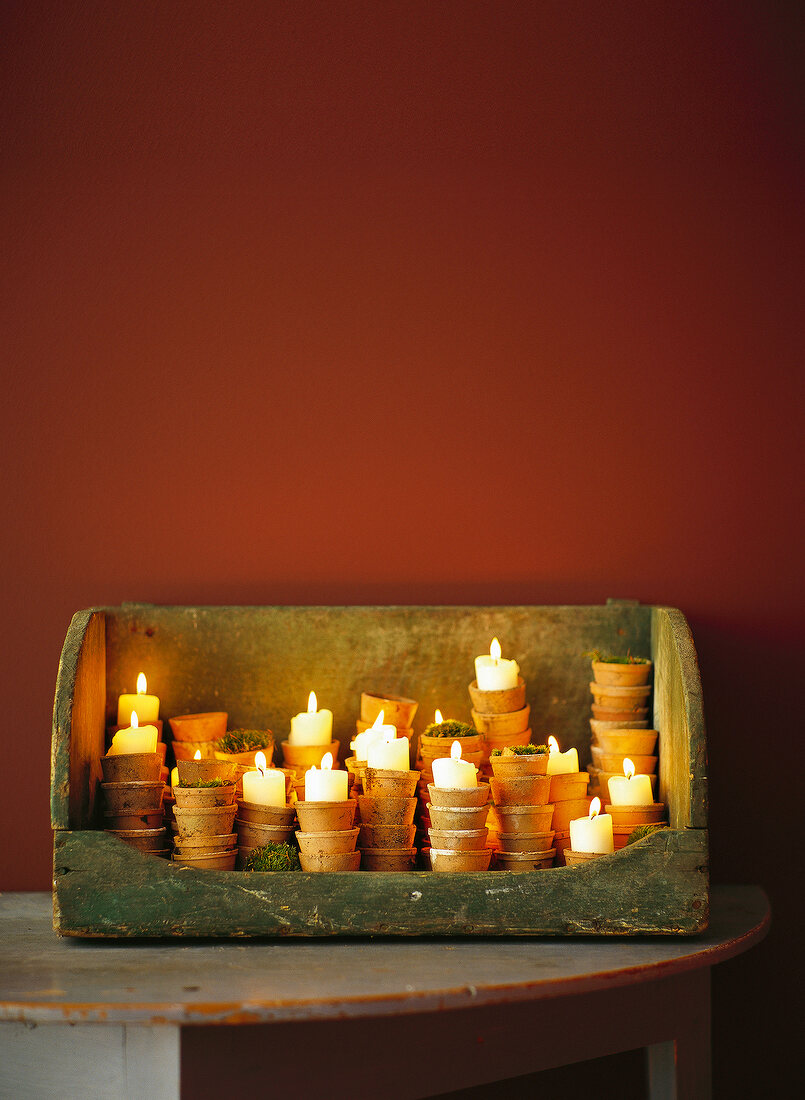 Wooden container with lit candles in small candle pots