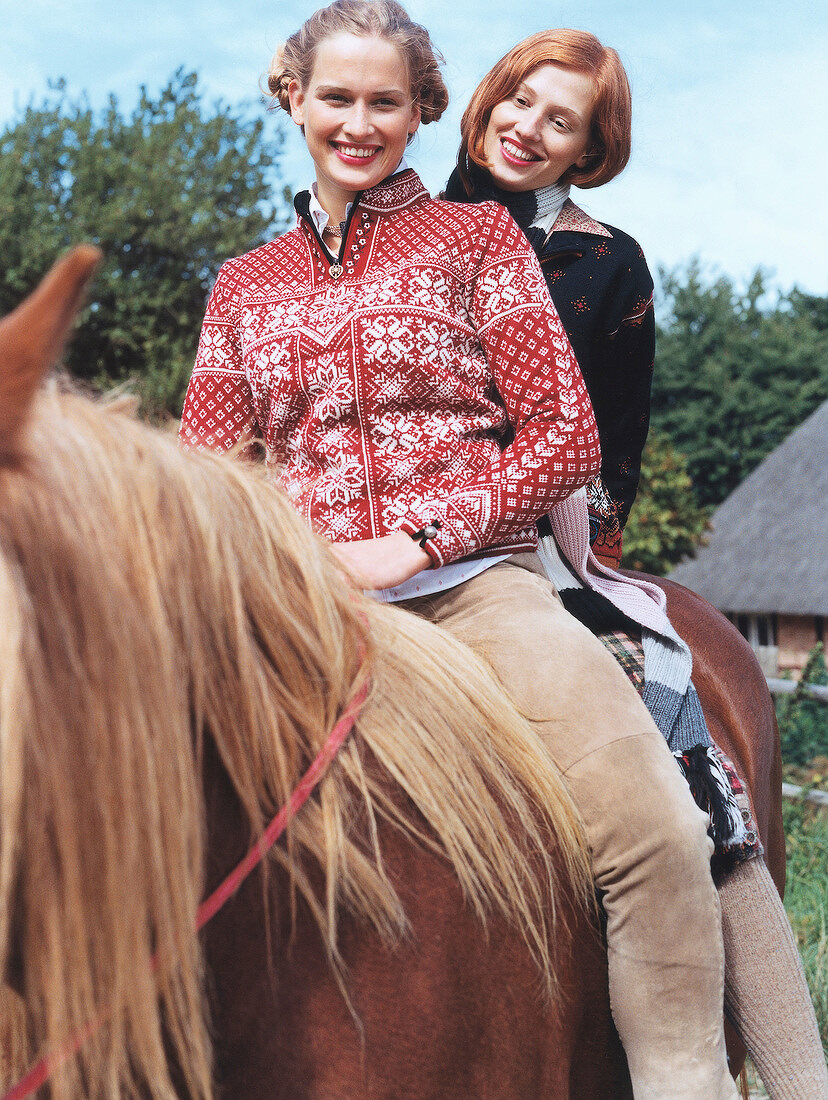 Cheerful women wearing traditional costumes riding a horse, smiling