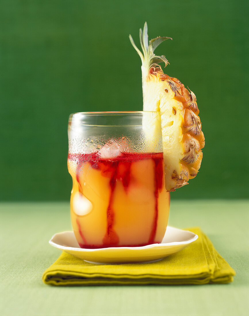 Ananas - Grenadine Drink in einem Glas mit einer Ananas dekoriert
