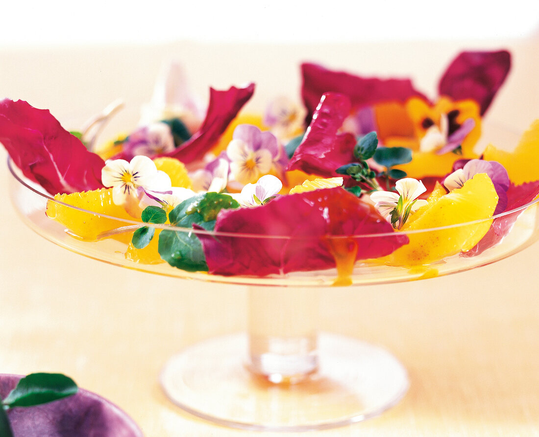 Close-up of salad with edible flowers and pansies on glass dish