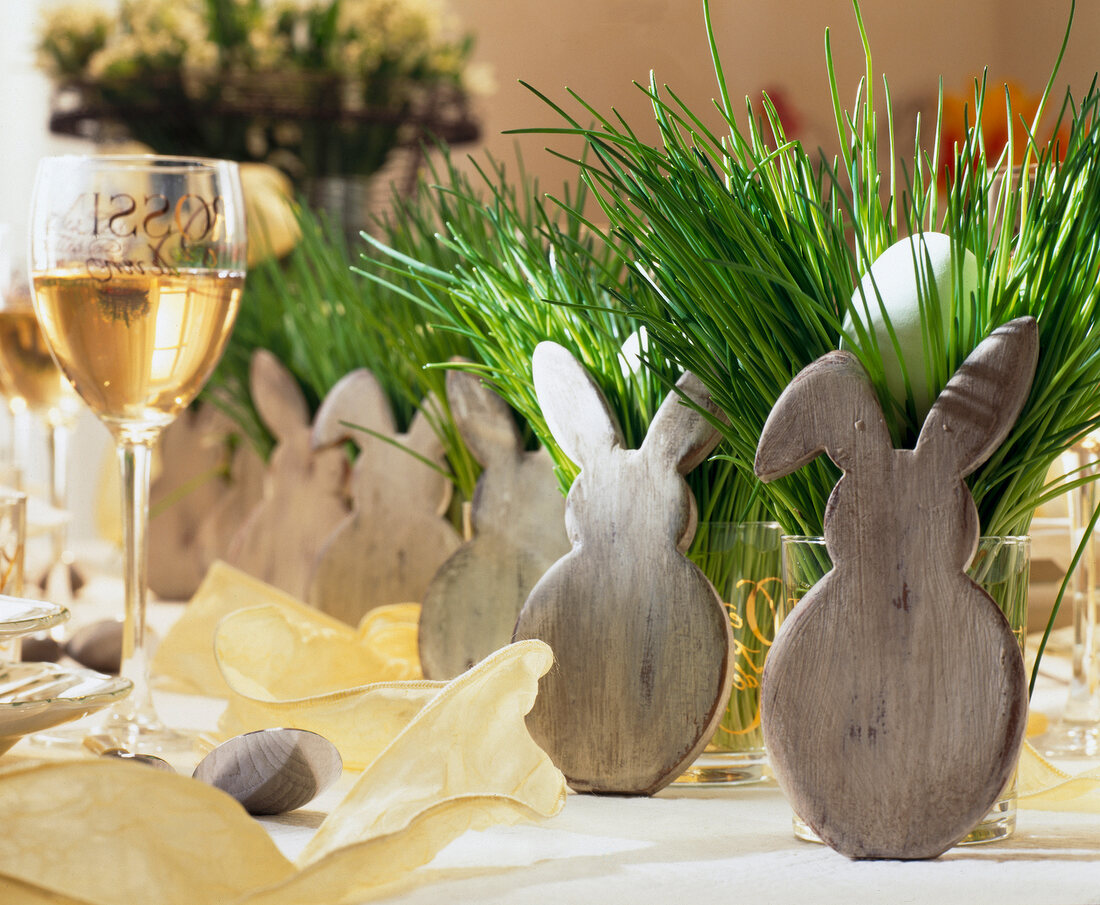 Wooden Easter bunny in front of glass cups with chives