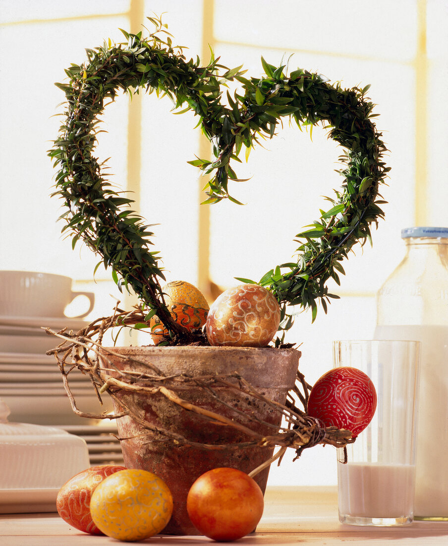 Heart shaped wreath in pot with colourful decorated eggs