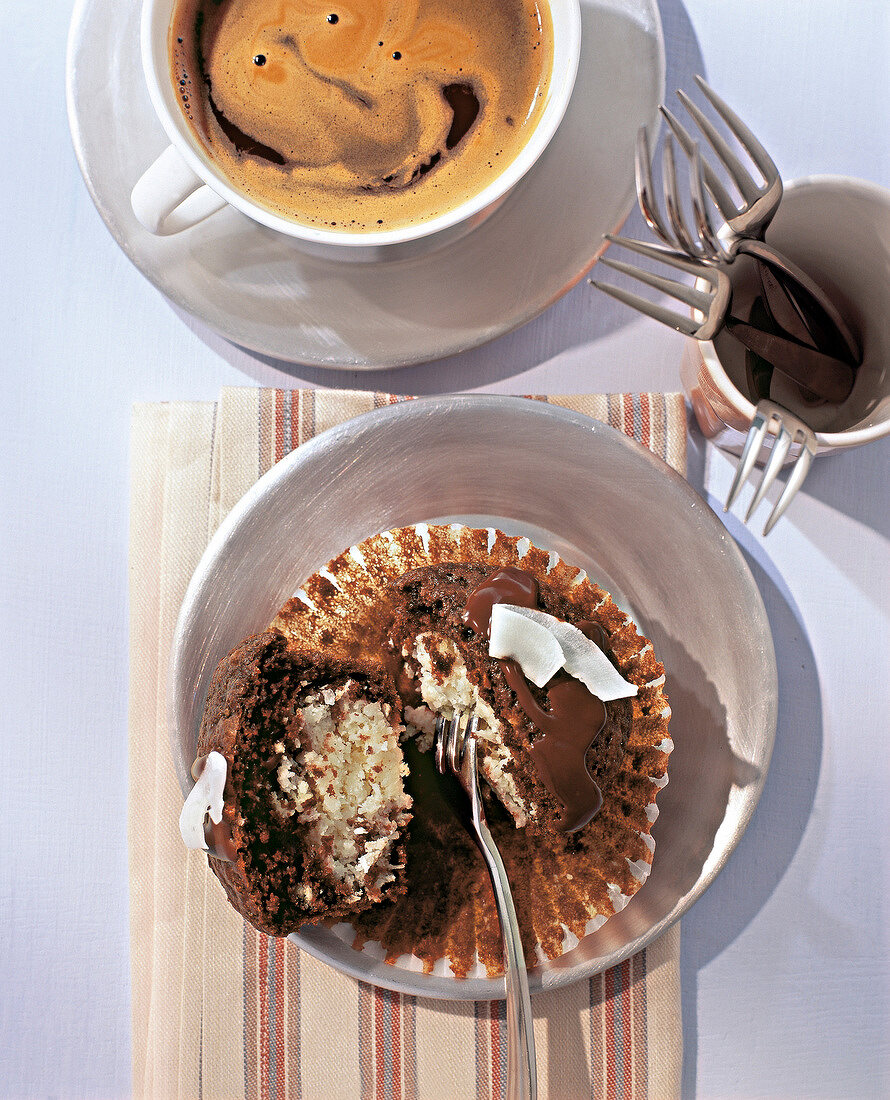 Chocolate and coconut muffin on plate with cup of coffee, overhead view