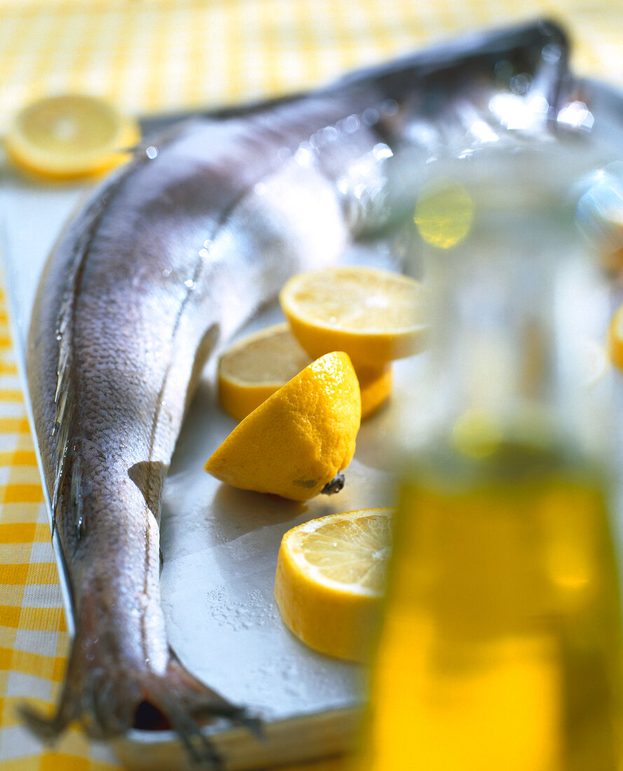 Close-up of hake fish with lemons on tray