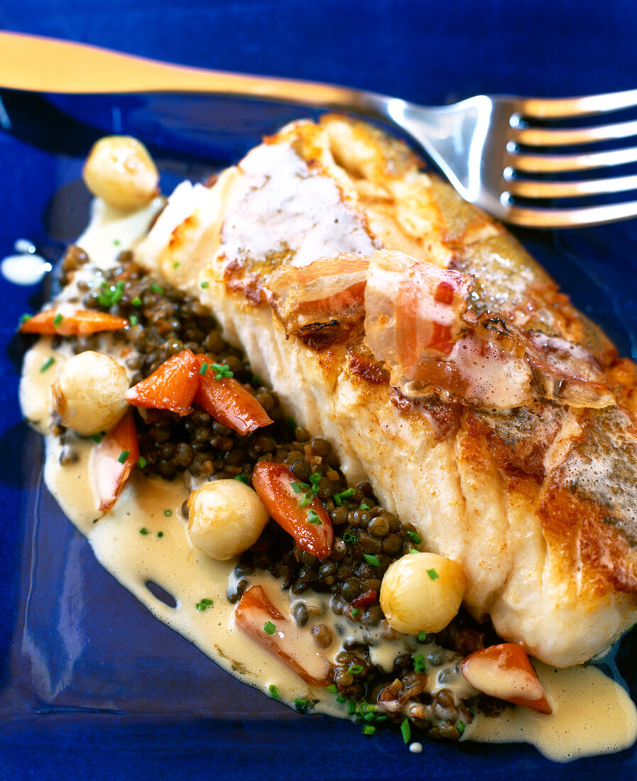 Close-up of fried cod supreme with lentils and mustard sauce