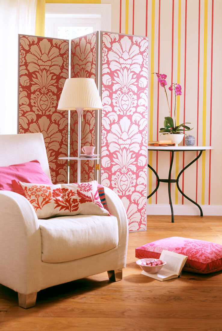 Living room with striped wallpaper, armchair, cushions and wooden floor