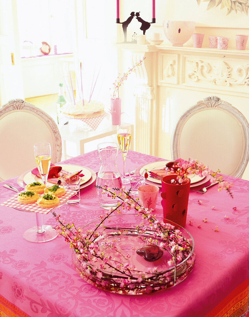 Laid dining table with pink table cloth and decorations