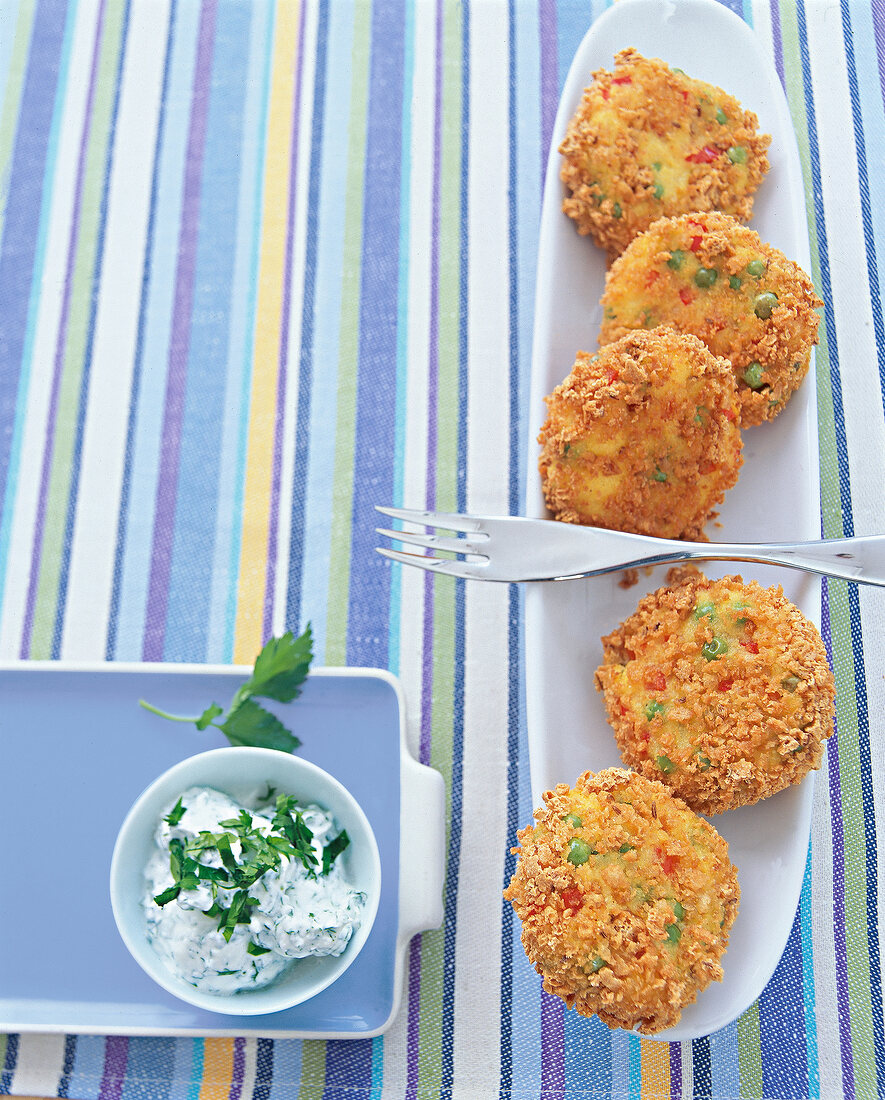 Polenta and vegetable patties on serving dish with dip