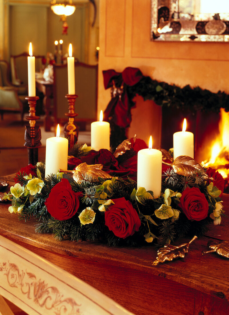 Close-up of Christmas wreath decorated with roses and lit candles