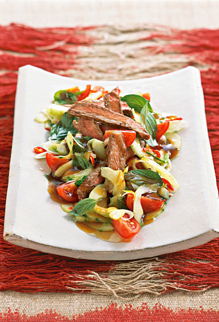 Close-up of Yum Nua spicy beef salad with marinated meat on plate